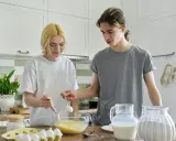Para nastolatków przygotowuje ciasto w kuchni, mieszając składniki w misce.