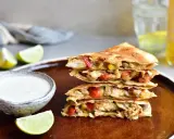 Stos **quesadilli z kurczakiem**, papryką i serem, podane z dipem i limonką.