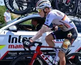 Radfahrer Georg Zimmermann mit aufgeschürftem Knie fährt neben dem Begleitfahrzeug des Teams Intermarché-Wanty.