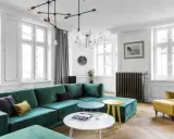 Zielona kanapa w salonie inspiracje: nowoczesny salon z dużą, welurową kanapą w kolorze butelkowej zieleni, żółtym fotelem i okrągłymi stolikami.