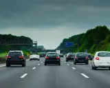 Ruch samochodów na niemieckiej autostradzie A8 pod pochmurnym niebem. Widać kilka czarnych i jeden biały samochód jadący pasem.