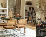 Ambiance chaleureuse pour aménager salle à manger : chaises cannées, table dressée avec bougies, fruits et feuillage.