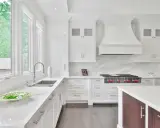 Cocina moderna y luminosa con muebles blancos, encimeras de cuarzo y electrodomésticos de acero inoxidable. Perfecta para pintar muebles de cocina y darles un nuevo aire.