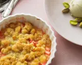 Rhabarber-Crumble in weißer Auflaufform, daneben eine Kugel Eis mit Pistazien. Ein köstliches Rhabarber Dessert.