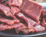 Suszone plastry wołowiny na czarnym talerzu. Idealne do przekąski, gdy szukasz prostego beef jerky przepis.