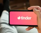 Dłoń trzyma smartfon z logo popularnych portali randkowych Tinder.