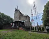 Kamienna wieża i maszty telekomunikacyjne na **chełmiec szczyt**. Drewniana przybudówka z flagami Polski.