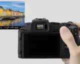 Immagine di una fotocamera con un mirino elettronico che mostra un canale con case colorate e barche.