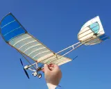 Ein handgefertigtes Modellflugzeug mit blau-weißen Flügeln, gehalten von einer Hand, bereit zum Flug. Ein echter slow flyer.