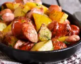 Pyszne ziemniaki po cabańsku, pieczone z kiełbaską i koperkiem, podane w żeliwnej patelni.