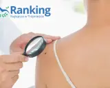 Dermatolog ogląda pieprzyk pod lupą na ramieniu pacjentki.