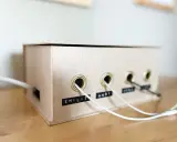 Kreative ladekabel aufbewahrung selber machen aus einem Karton. Kabel sind ordentlich durch Ösen geführt und beschriftet.