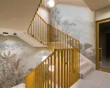 Habillage mur cage d'escalier avec un décor tropical en camaïeu. Escalier en marbre et rambarde en bois doré.