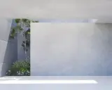 Moderne Architektur mit transluzentem Beton und grüner Vegetation. Sonnenlicht fällt durch eine Öffnung und beleuchtet den Boden.