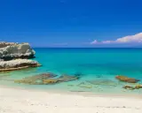 Spiaggia di Santa Domenica con rocce bianche e mare cristallino sotto un cielo azzurro.