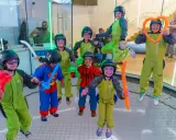 ¡Diversión volando en Madrid! Niños con trajes verdes y cascos disfrutan de la experiencia, algunos con globos. ¡Un fin de semana inolvidable!