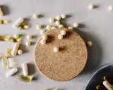 Kapseln und Pillen, darunter auch solche, die bei **Magnesium zum Abnehmen** helfen könnten, liegen verstreut auf hellem Untergrund.