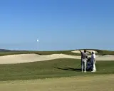 Zwei Golfer planen ihren nächsten Schlag auf dem Valderrama Golfplatz, mit einem Bunker und dem Fahnenmast im Hintergrund.