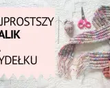 Kolorowy szal na szydełku, gotowy do noszenia. Widać też kłębek włóczki, szydełko i nożyczki.