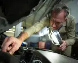 Mechanik sprawdza bezpieczniki w Grande Punto, używając lampy inspekcyjnej.