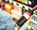 Kobieta wybiera wino, zastanawiając się, czy to jej osobisty wysokofunkcjonujący alkoholik test.