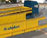 Montaje de una plataforma de descarga obra con vigas amarillas y un camión azul.