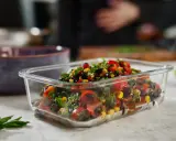 Frischer schwarze bohnen salat mit Mais, Tomaten und Kräutern in einer Glasbox.