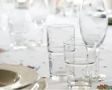 Stół nakryty obrusem z wzorami, na nim talerze i szklanki. Szkło borokrzemowe jest bezpieczne, nie ma szkodliwość.