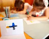 Dzieci rysują krzyże, ucząc się o religii w szkole. Na pierwszym planie symbol wiary.
