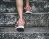 Pomarańczowe buty sportowe na siłownię, idealne na trening, wspinają się po betonowych schodach.