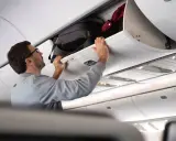 Man stänger bagagehyllan med handbagage ombord på ett flygplan från Austrian Airlines.