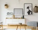 Un mueble blanco resalta sobre una pared clara, complementado con cestas de mimbre y arte africano. El color de pared para muebles blancos es neutro y elegante.
