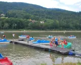 Wakacyjny dzień na Jeziorze Żywieckim. Ludzie pływają na rowerach wodnych, czując się jak na karaibskiej plaży.