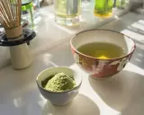 Zwei Schalen auf einem Tisch: eine mit grünem Pulver, die andere mit aufgebrühtem Sencha Tee. Die Wirkung von Sencha Tee ist belebend.