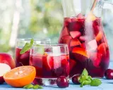 Une carafe et des verres de sangria rouge remplis de fruits frais, parfaits pour une recette de sangria rouge estivale.