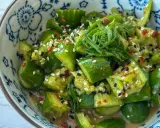 Erfrischender asiatischer Gurkensalat mit Sesam, Chili und Frühlingszwiebeln in einer blumengemusterten Schüssel.