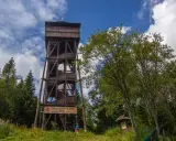 Drewniana wieża widokowa na Magurkach zaprasza do podziwiania panoramy. Wokół bujna zieleń i błękitne niebo.