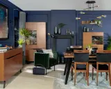 Inspiracje granatowa ściana w salonie: elegancka jadalnia z drewnianymi meblami, aksamitnym fotelem i nowoczesnym oświetleniem.