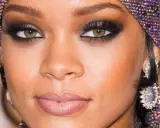 Occhi verdi intensificati da un trucco smokey eye audace, con labbra nude e un copricapo scintillante.