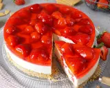 Ein saftiger erdbeerkuchen ohne backen mit frischen Erdbeeren und rotem Tortenguss. Ein Stück ist bereits angeschnitten.