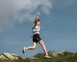 Läuferin im Sprung über felsiges Gelände, um ihre Ausdauer zu verbessern.