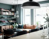 Vardagsrum med bokhylla i 50-talsstil, soffa i läder och stora fönster.
