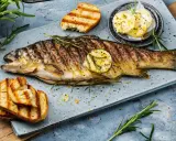 Perfekt gegrillte Forelle mit Kräutern, Zitronenscheibe und geröstetem Brot. Ein Genuss für jeden Fischliebhaber.