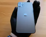 Ręka w czarnej rękawiczce trzyma elegancki iPhone 11 czarny. Obok leży czarne pudełko.