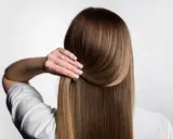 Capelli lisci e setosi, senza crespo, grazie a una routine efficace. La mano accarezza la chioma lucente.