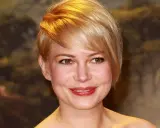 Uśmiechnięta kobieta z blond fryzurą i okrągłą twarzą, z rumieńcami na policzkach i błyszczącymi ustami.