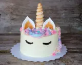 Ein magischer einhorn kuchen mit pastellfarbener Glasur, einem gedrehten Horn und süßen Wimpern.