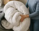 Persona saca una colcha de plumas de la lavadora. ¡Qué decepción, la almohada de plumas huele mal después de lavarla!