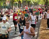 Läufer im Pulk auf einer Straße, einige mit Startnummern, die auf einen Marathon unter 4 Stunden hindeuten.