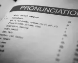Otwarta książka z hasłem "PRONUNCIATION". Lista słów i symboli fonetycznych pokazuje, czy angielski jest trudny.